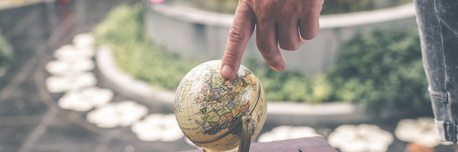 finger pointing to a location on a globe