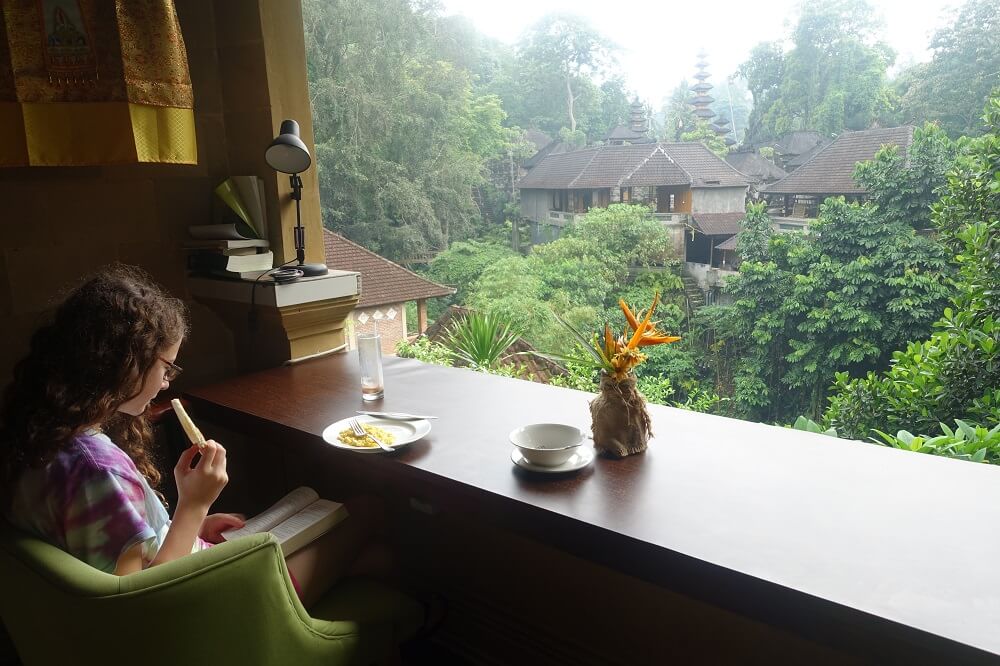 Girl reading at breakfast with beautiful view