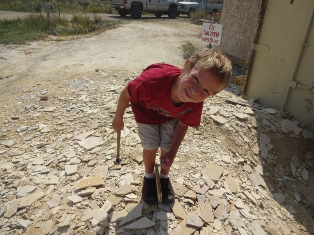 boy splitting fossil rock with mallet and chisel
