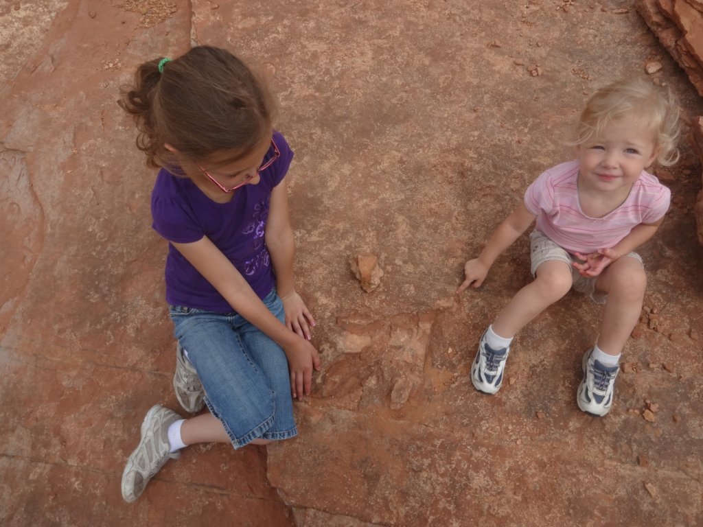 kids sitting by dinosaur track
