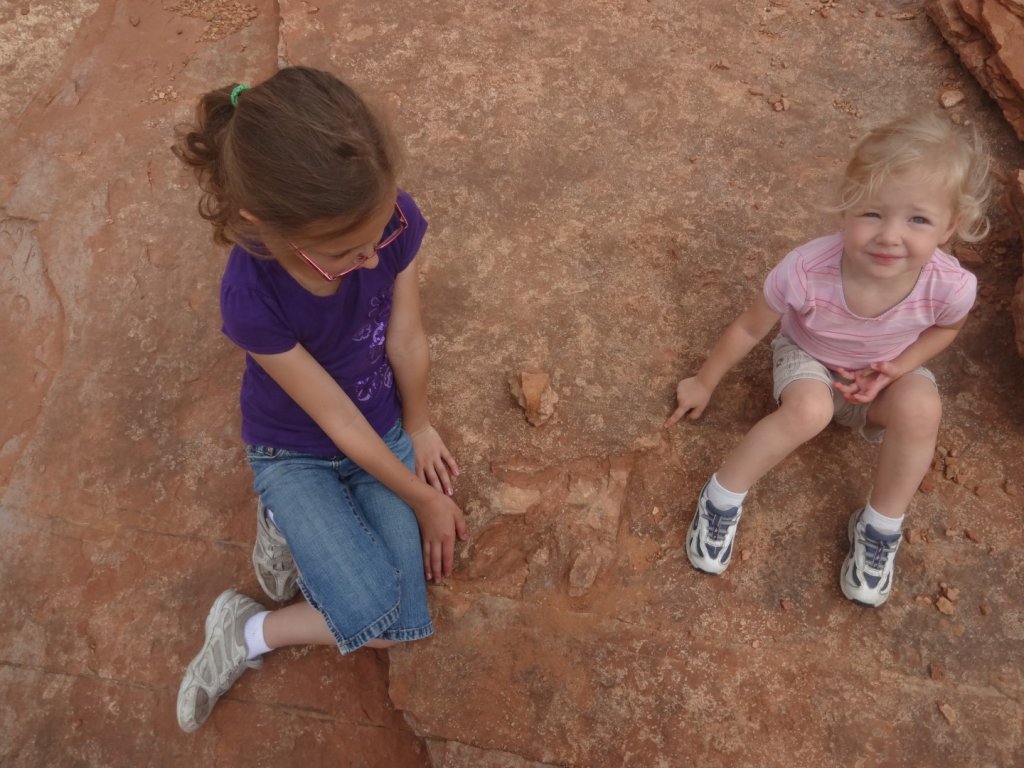 kids sitting by dinosaur track