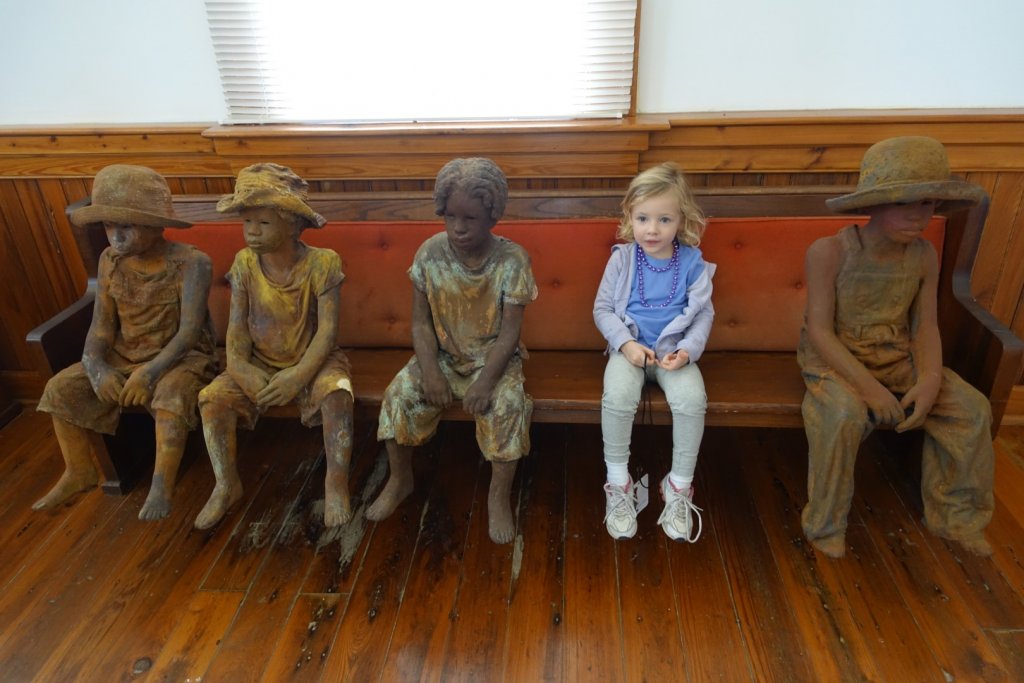 girl sitting with statues of slave children