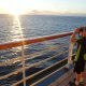 Boy looking into the ocean through binoculars from cruise ship
