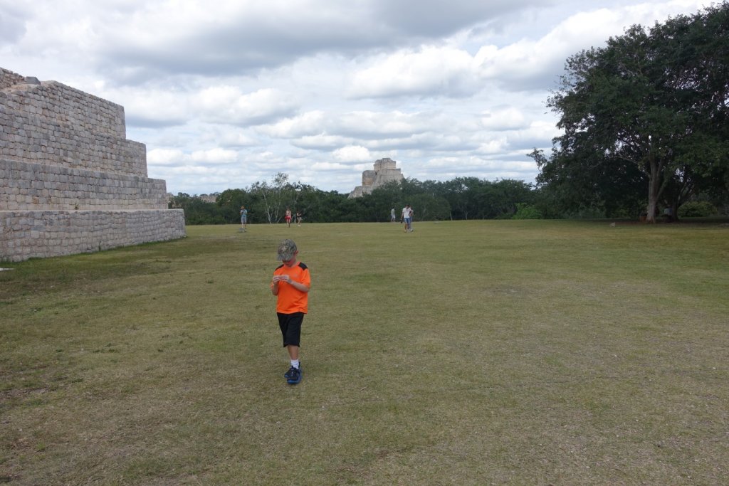 Boy holding a grasshopper with ruins in the background