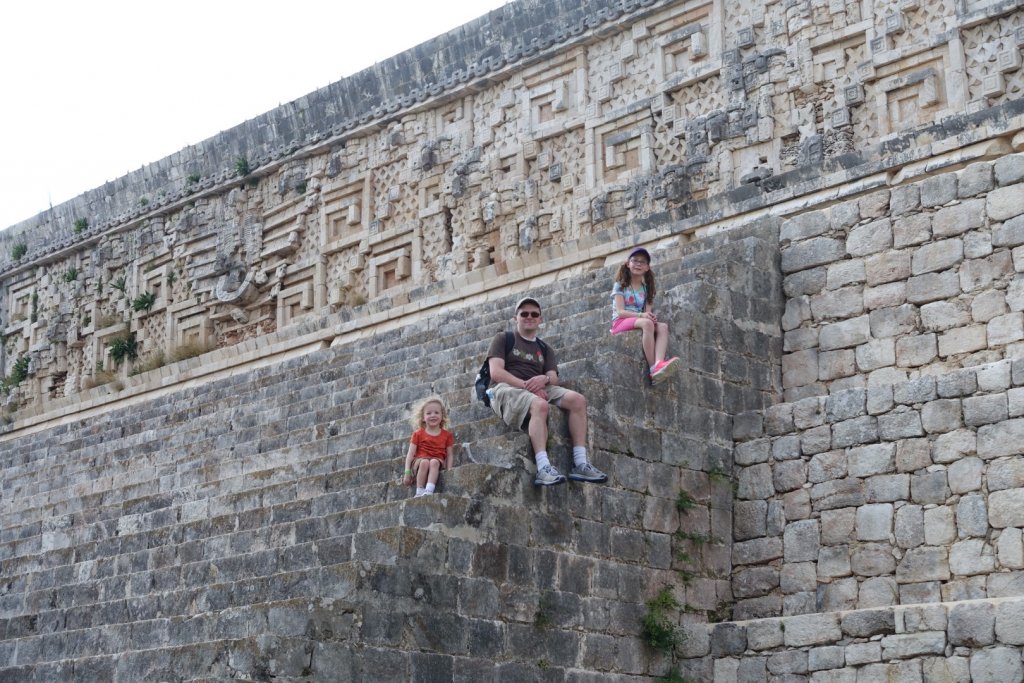 father and daughters sitting on steps of a Mayan temple