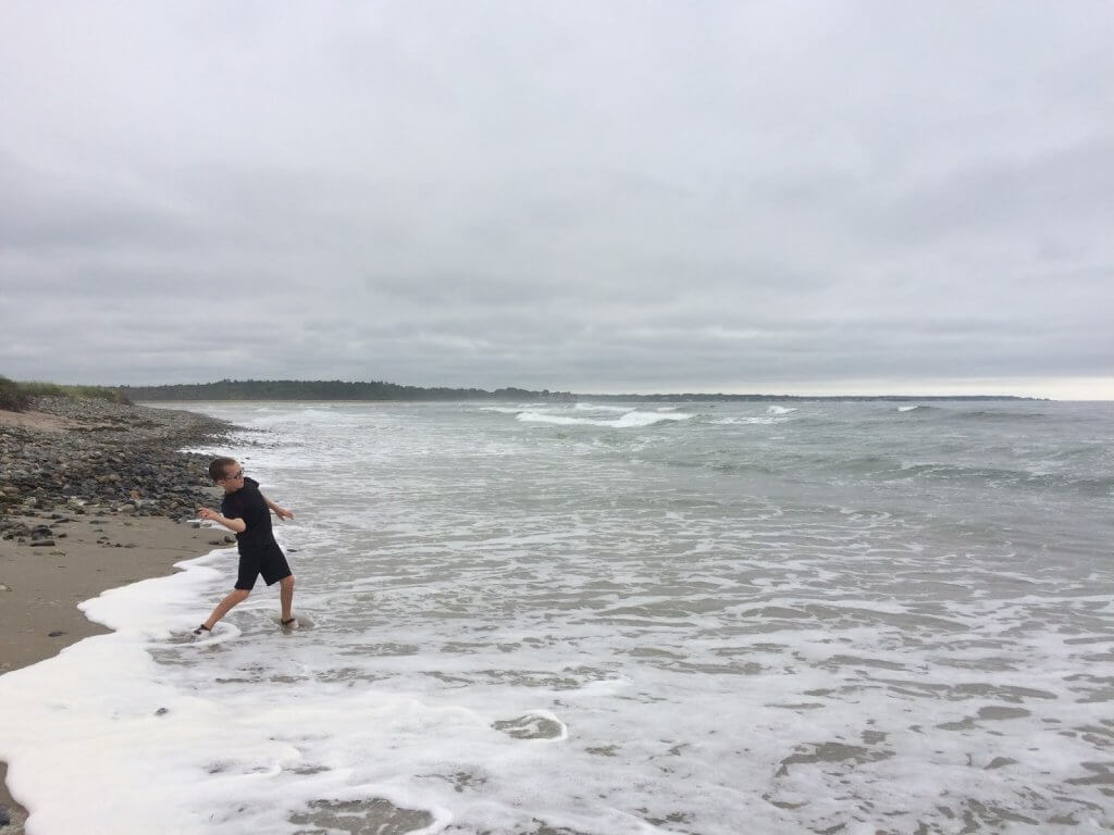 boy throwing rocks into the ocean