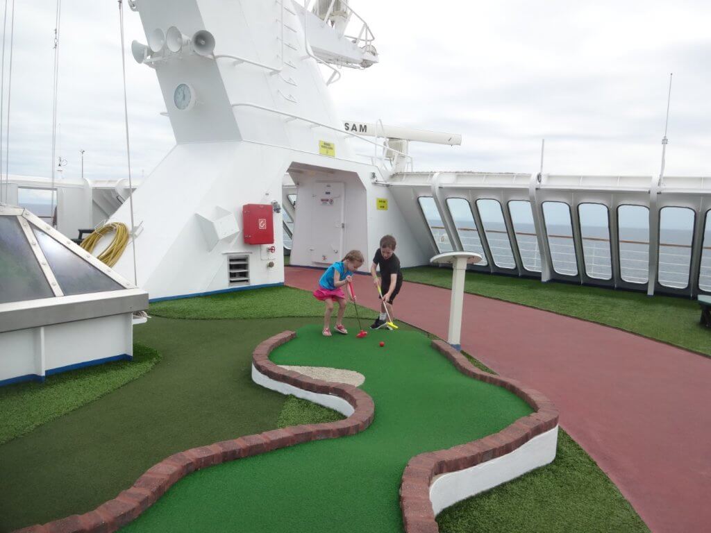 two kids playing mini golf on a cruise ship