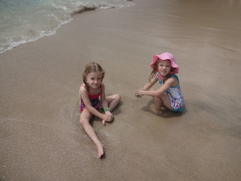 two girls playing in the sand on the beach