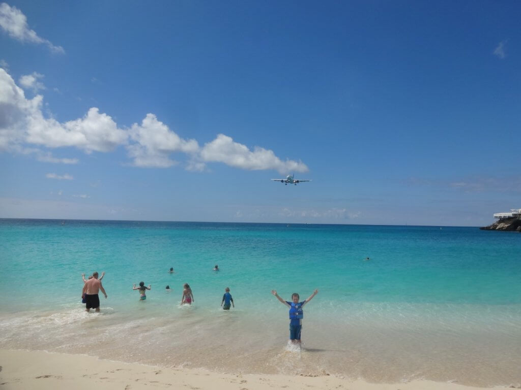 Boy in the ocean with an airplane overhead