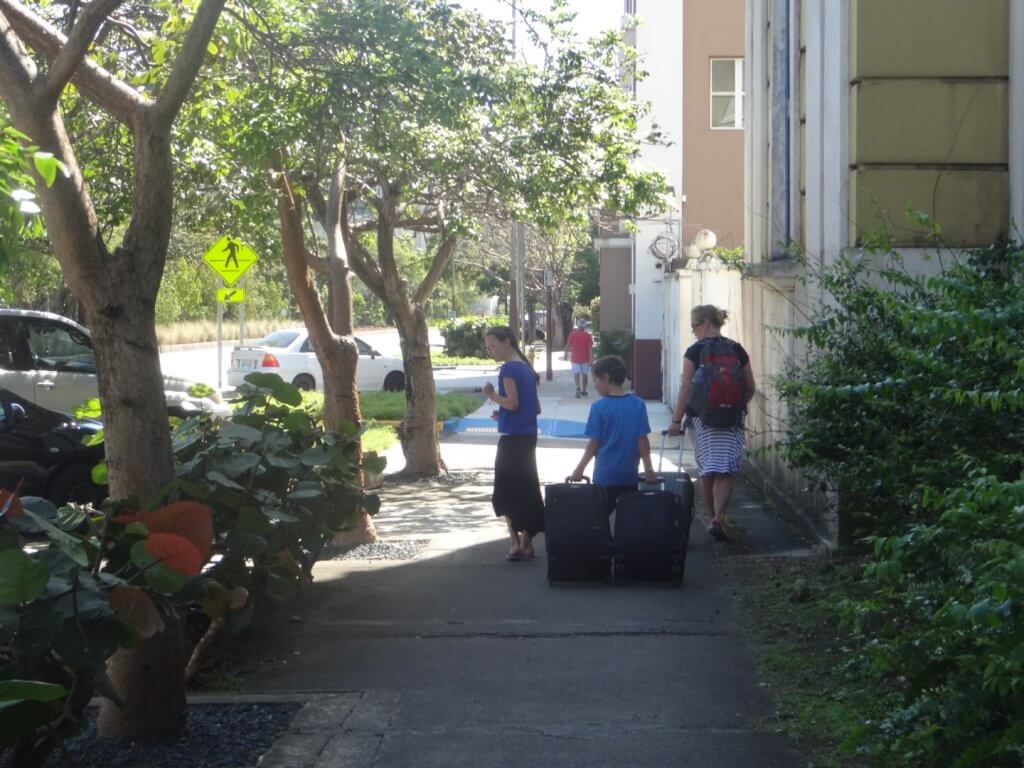 Mom and kids walking on the sidewalk with luggage