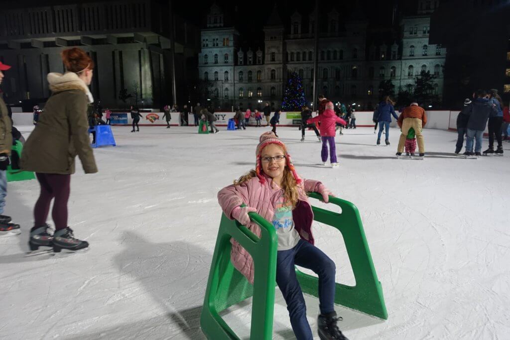 young girl ice skating with skate aid