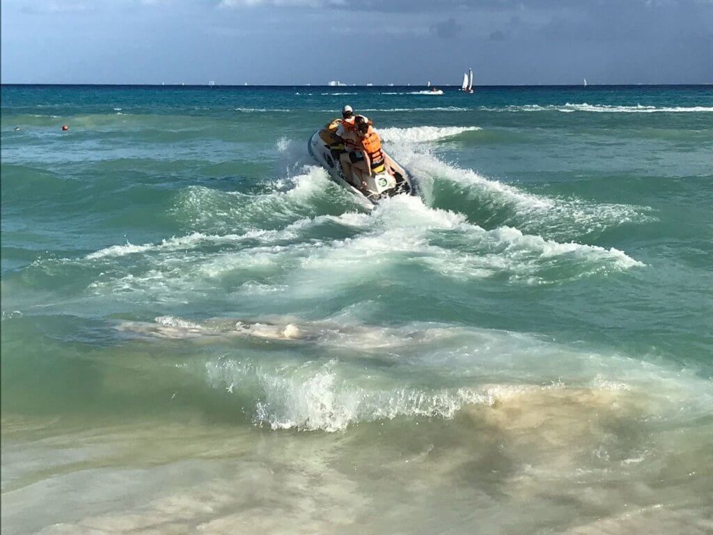 three people on a jet ski in the waves