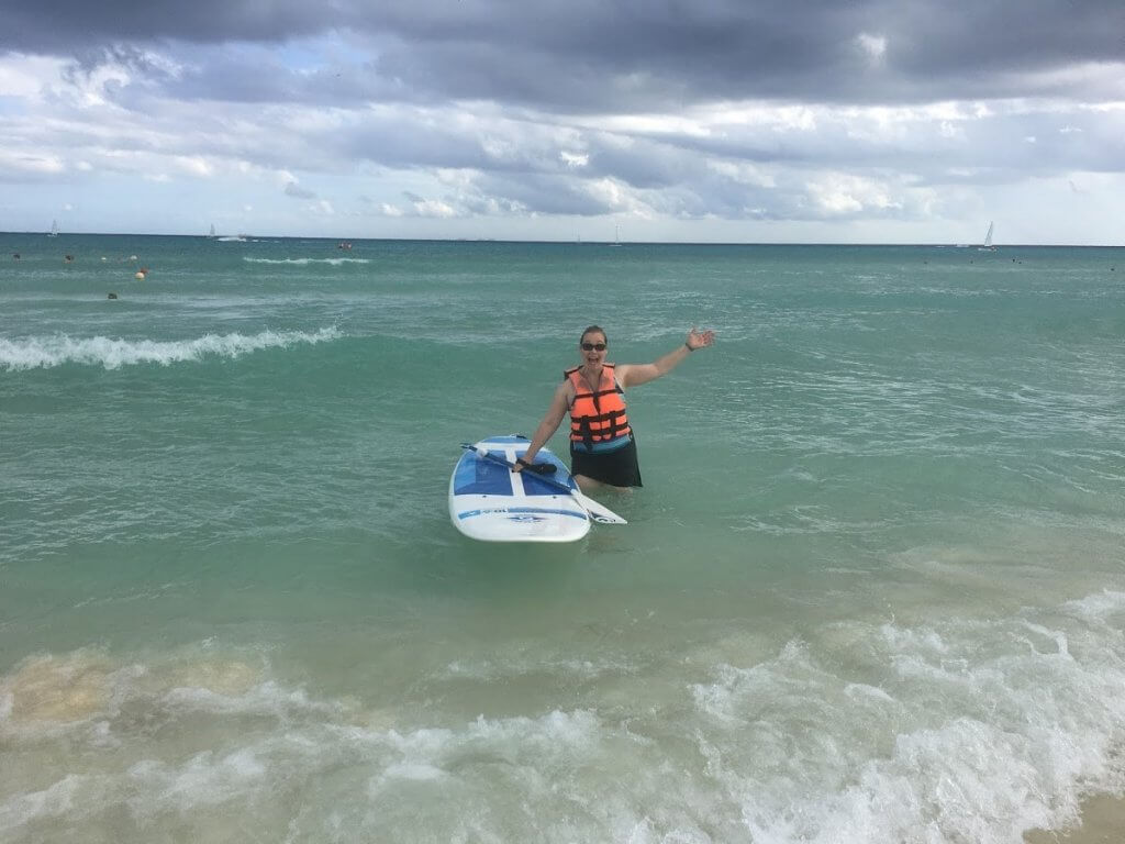 woman in the ocean with a stand up paddle board