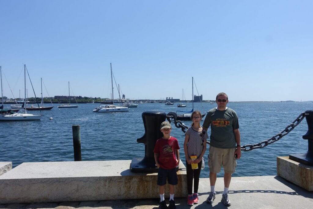 man and two kids in front of water