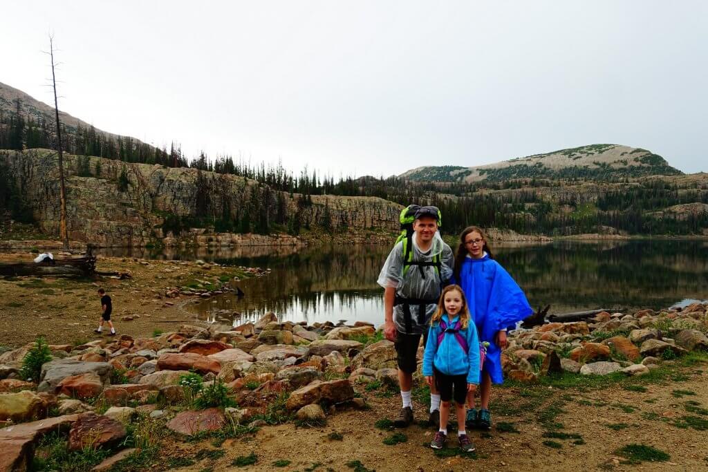 father and daughters hiking with ponchos