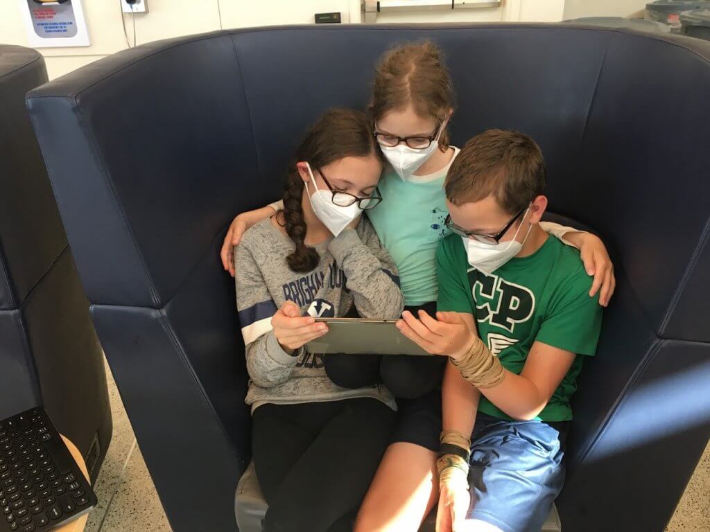 kids wearing masks and watching tablet