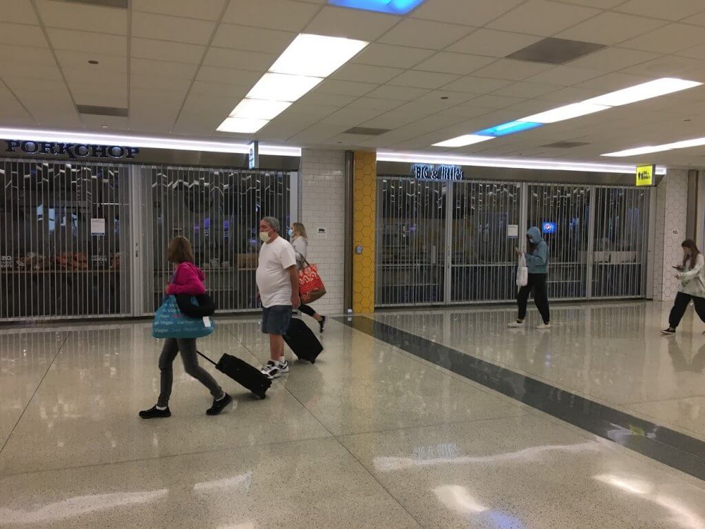 people in masks and closed stores in airport