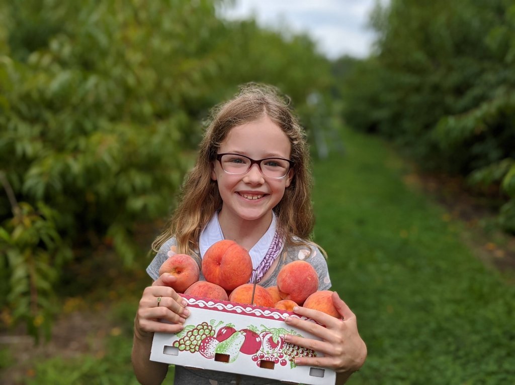girl holding box of peaches