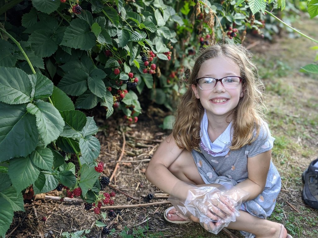 girl smiling by blackberry bushes