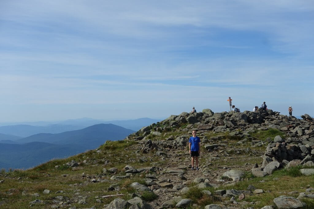 boy standing at top of mountain