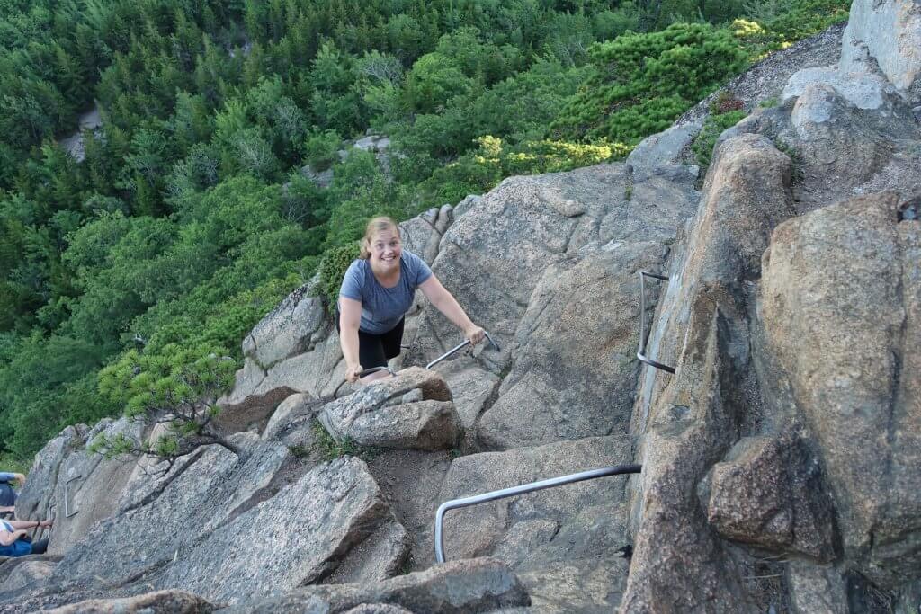 woman climbing metal rungs on mountain