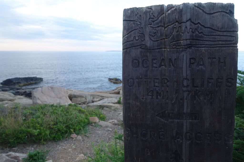 trail sign in front of ocean
