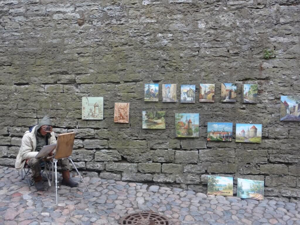 man painting pictures by wall