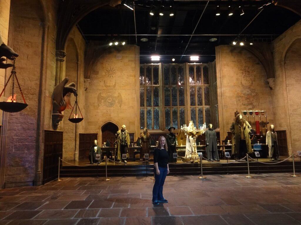 woman in front of costumed mannequins in large room