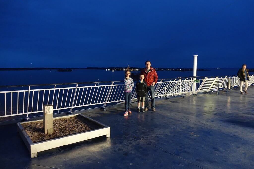 father and kids standing on ferry at night