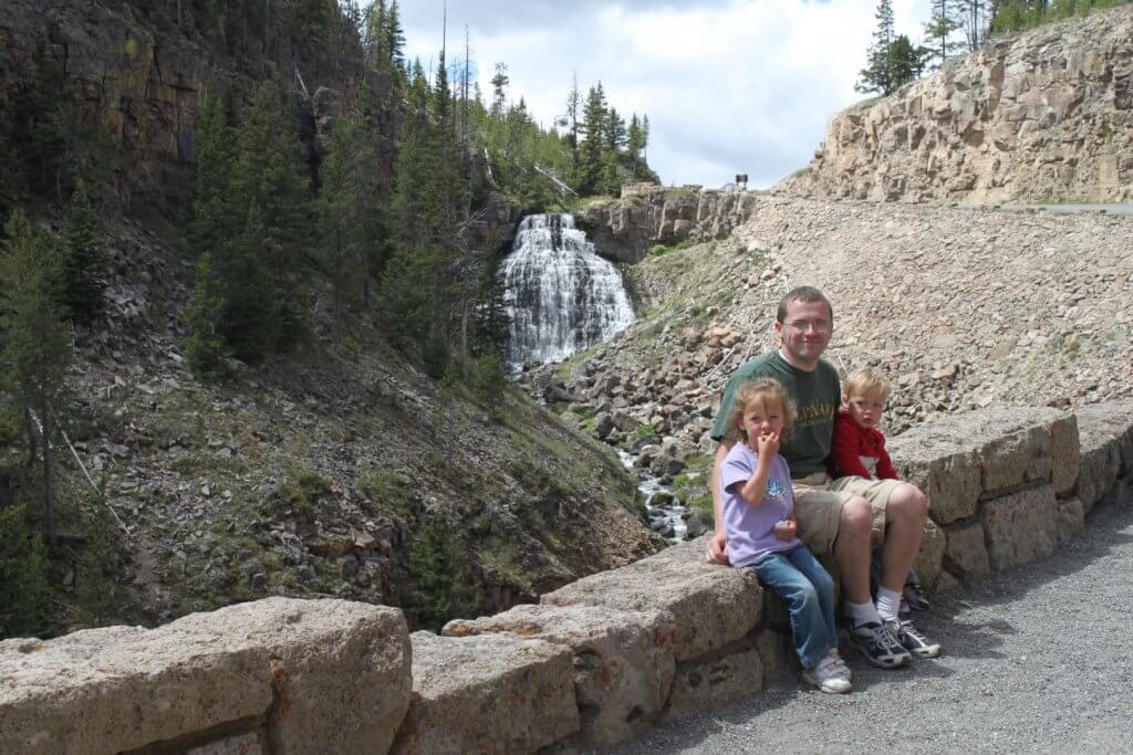 man and kids in front of waterfall
