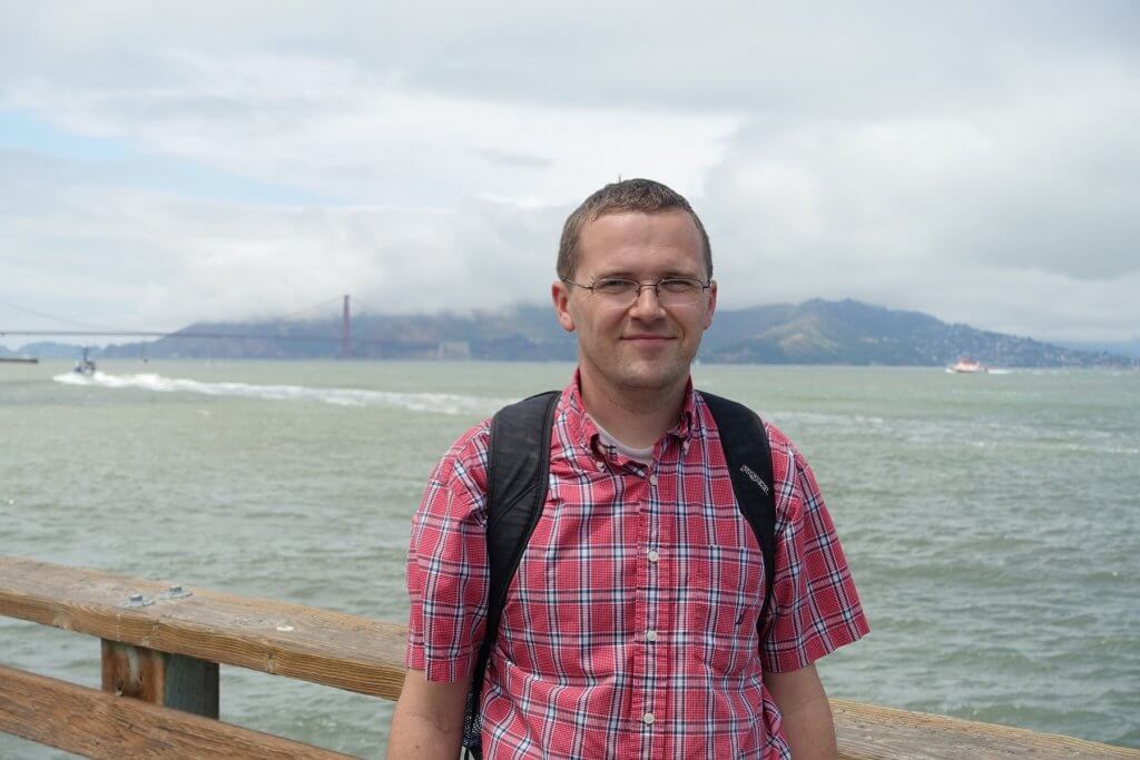 man with ocean and bridge in background