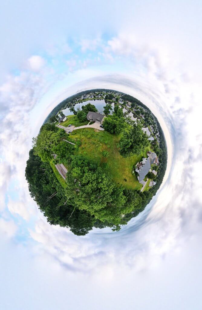 drone 360 degree picture of trees, houses, and lake