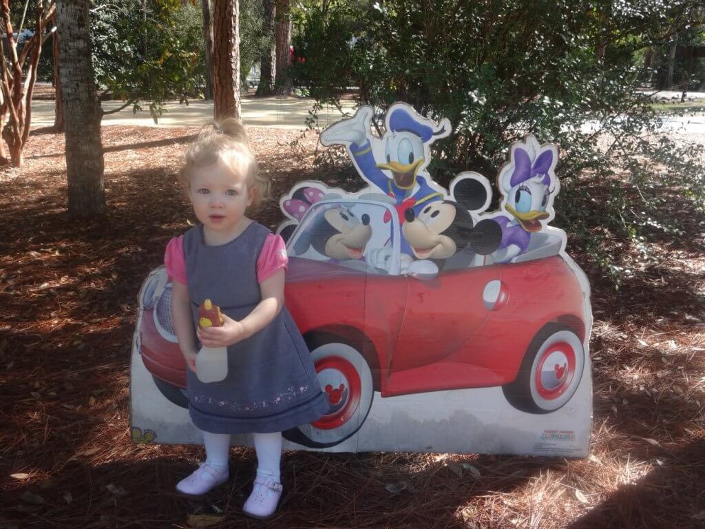 girl in a dress in front of Mickey Mouse sign