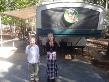 boy and girl holding lizards in front of camper trailer