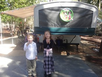 boy and girl holding lizards in front of camper trailer