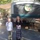 boy and girl holding lizards in front of camper trailer