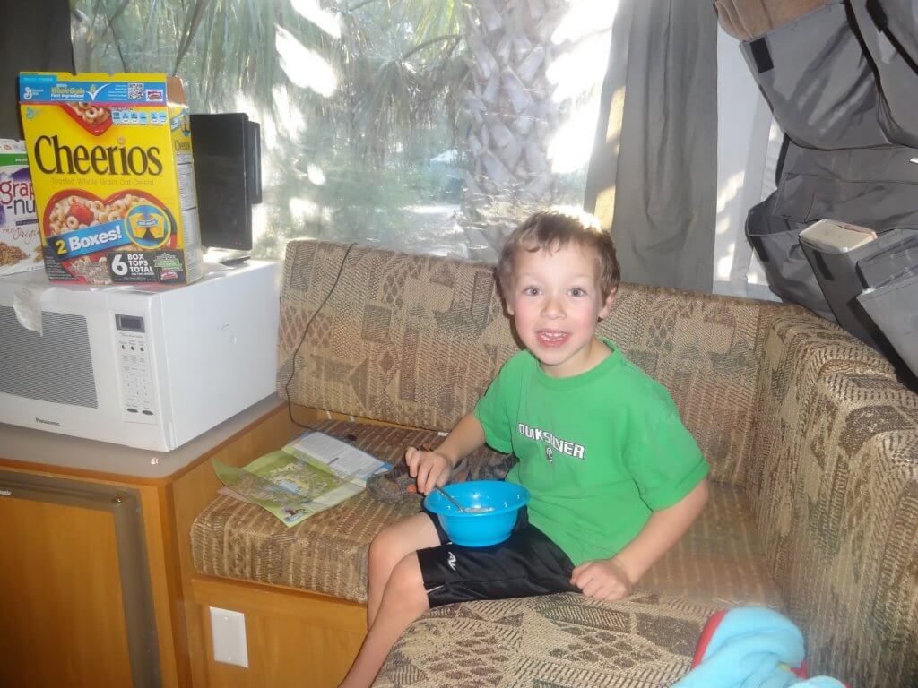 boy eating from a blue bowl on a couch