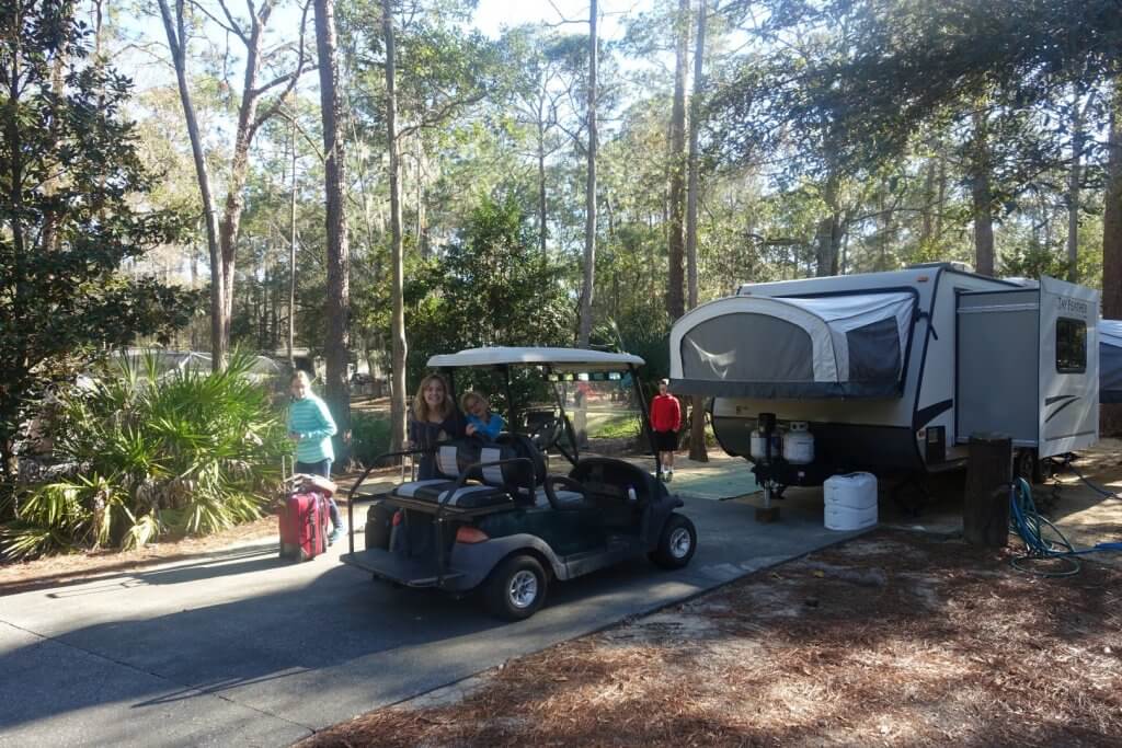 mother and kids with golf cart and pop-up trailer at campsite