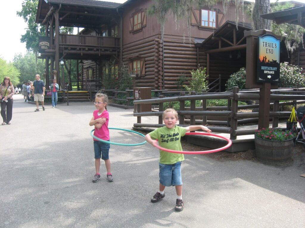 kids playing with hoola hoops in front of log building