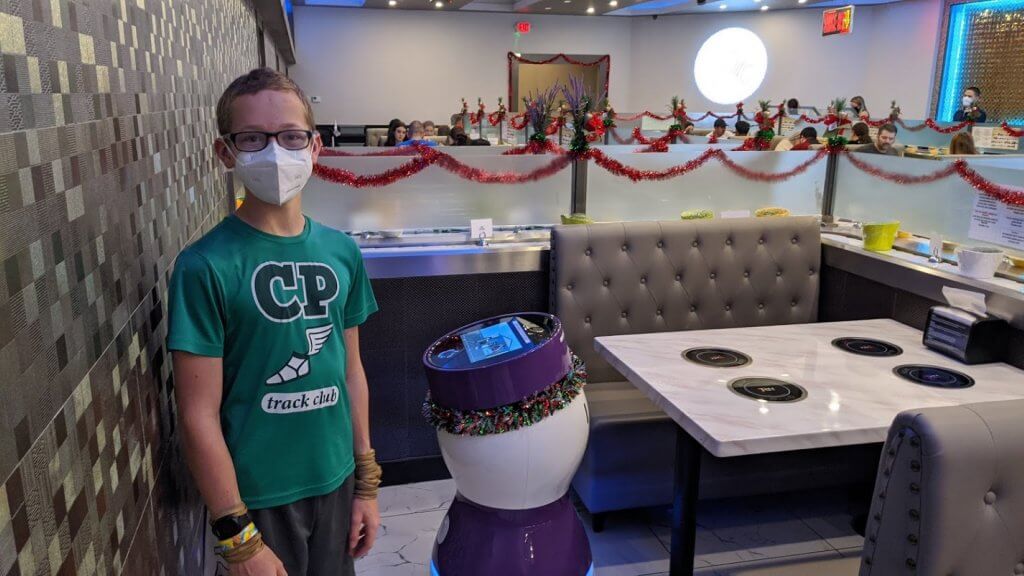 boy in a mask with robot in restaurant