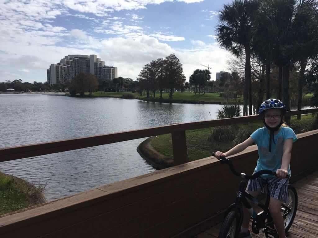 girl on bike in front of pond