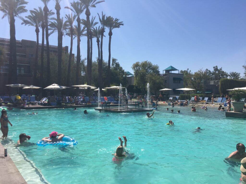 people swimming in large swimming pool with fountains