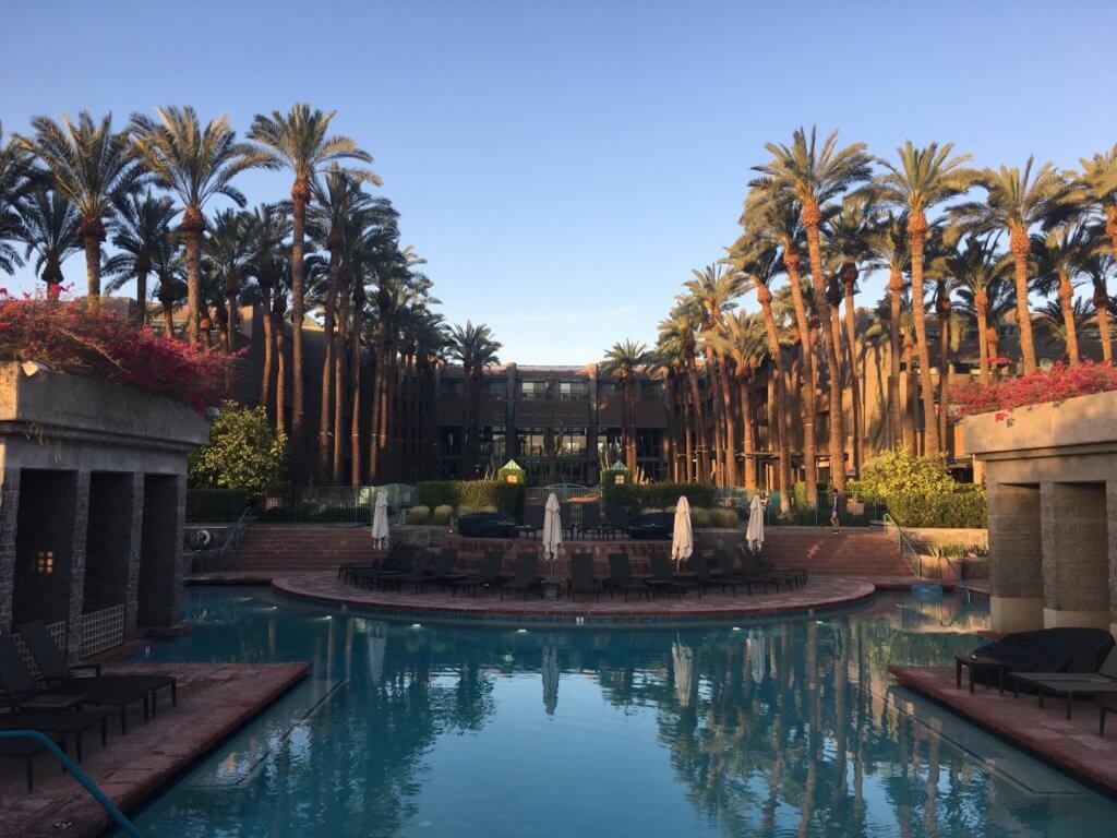 swimming pol with palm trees in front of hotel