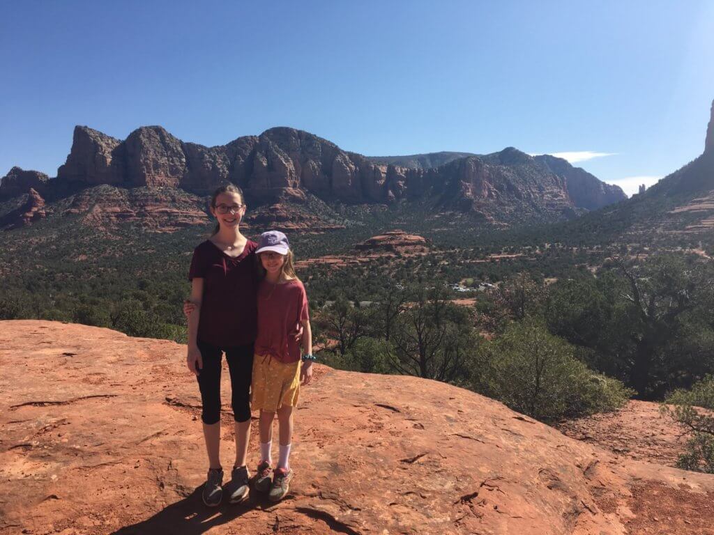 sisters on rock with mountains behind