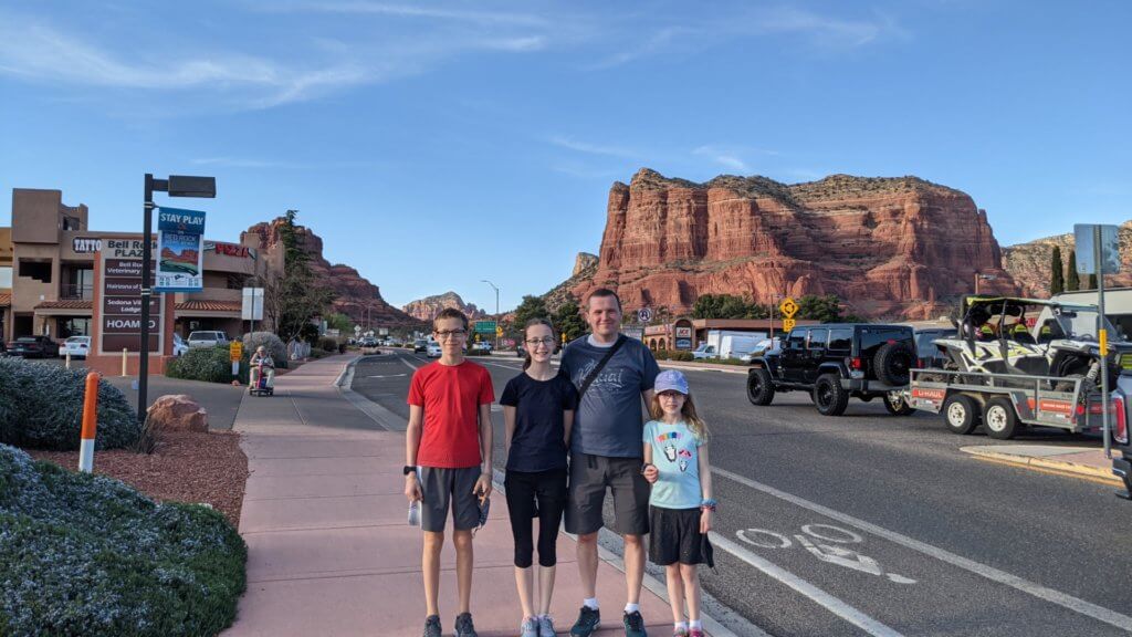 family in front of street and red mountains