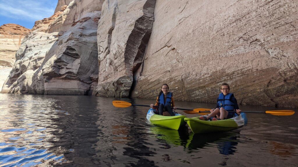kayakers on water in front of cliff face