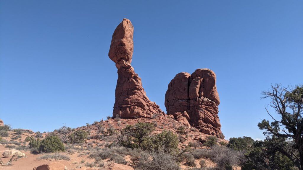 large rock balancing on rock pillar