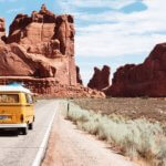 van driving on road with red rock cliffs