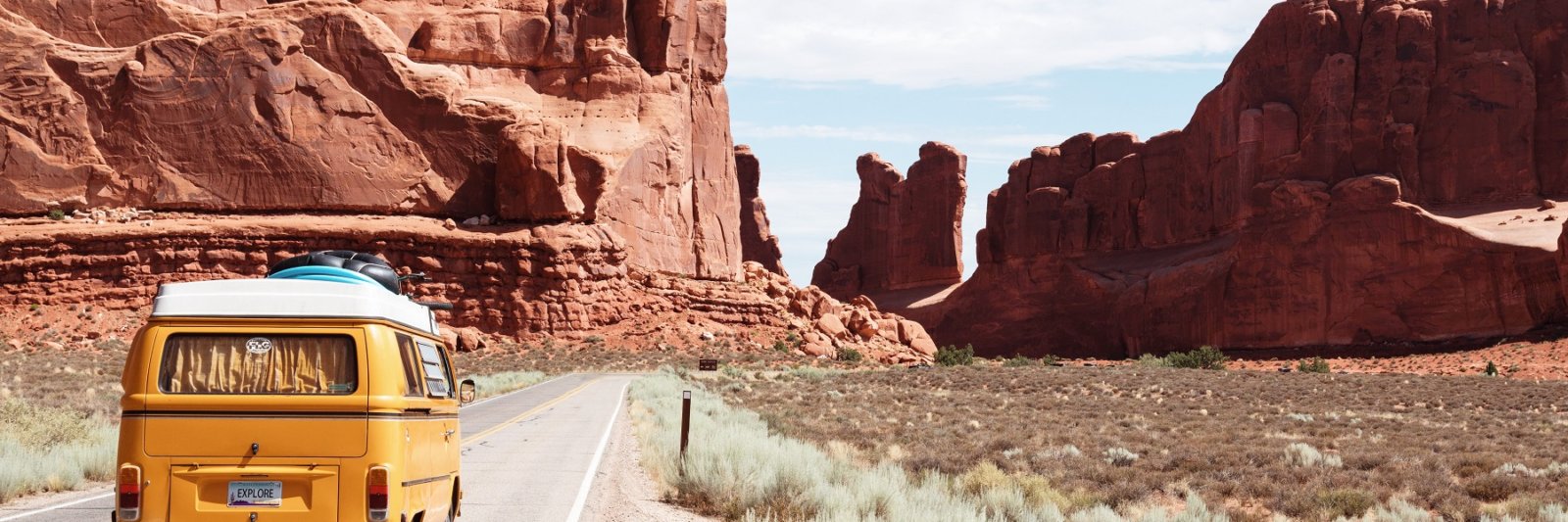 van driving on road with red rock cliffs