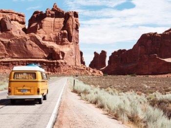 van driving on road with red rock cliffs